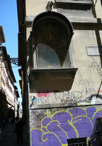 Madonna in tabernacle looks down on scrawled walls