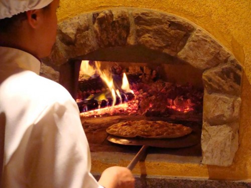 The pizzaiolo slides a pizza into the wood-burning oven