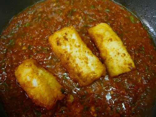 Fried salt cod simmering in a spicy tomato sauce